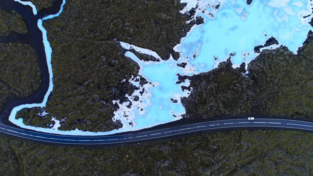 Straße durch Lavafelder vorbei an blauem Wasser der Blauen Lagune in Island
