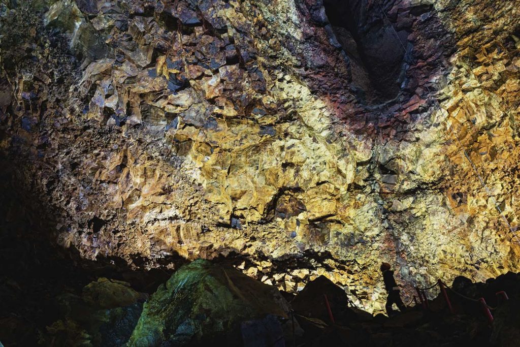 Beleuchtete Felswand tief im Inneren des Three Peaks Craters in Island bei einer Vulkantour.